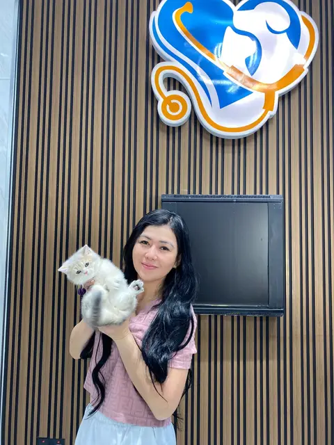A client with her cream kitten under the Petbook logo