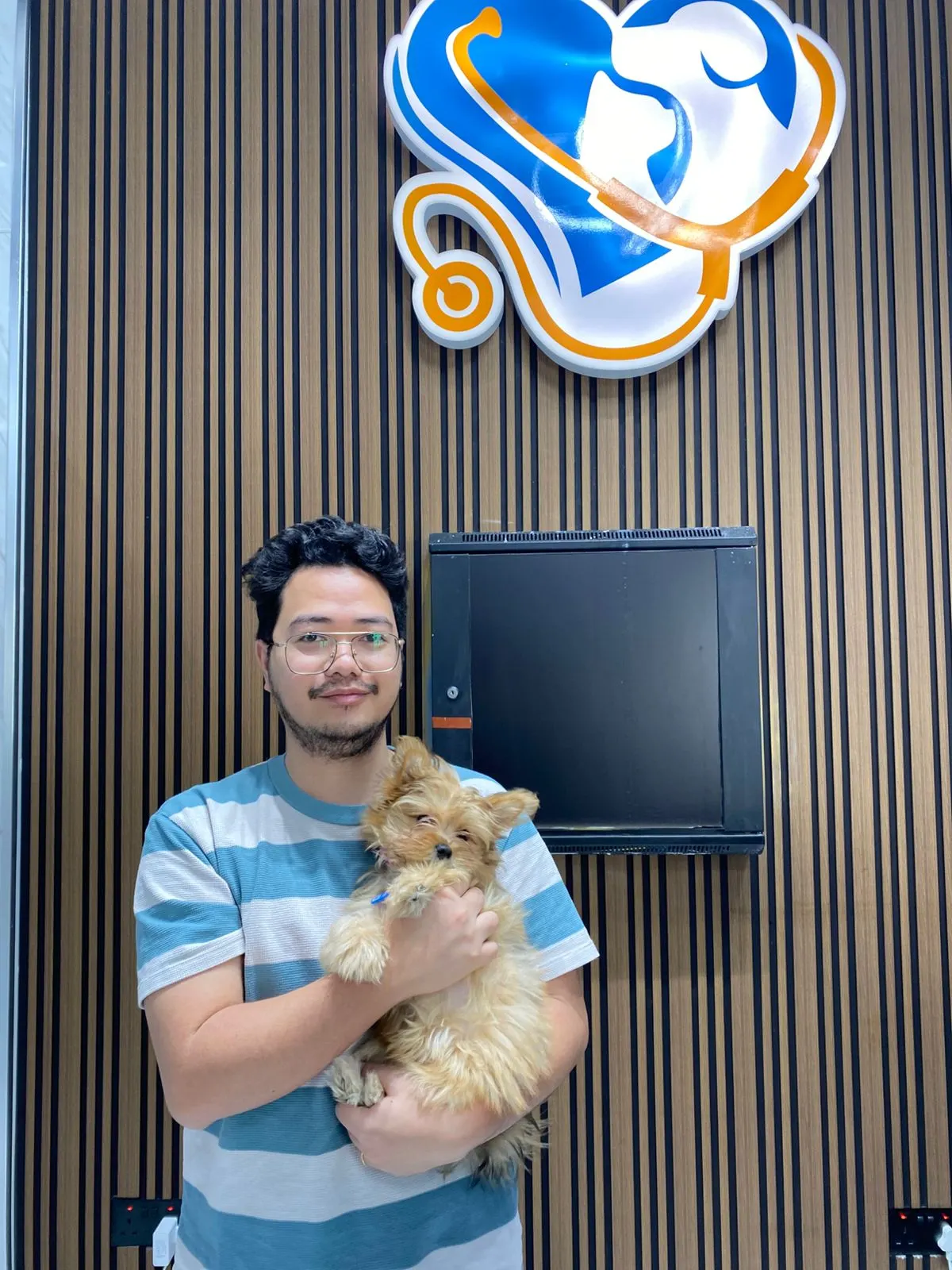 A client holding a small Yorkshire terrier at the Petbook reception desk in Al Quoz, Dubai
