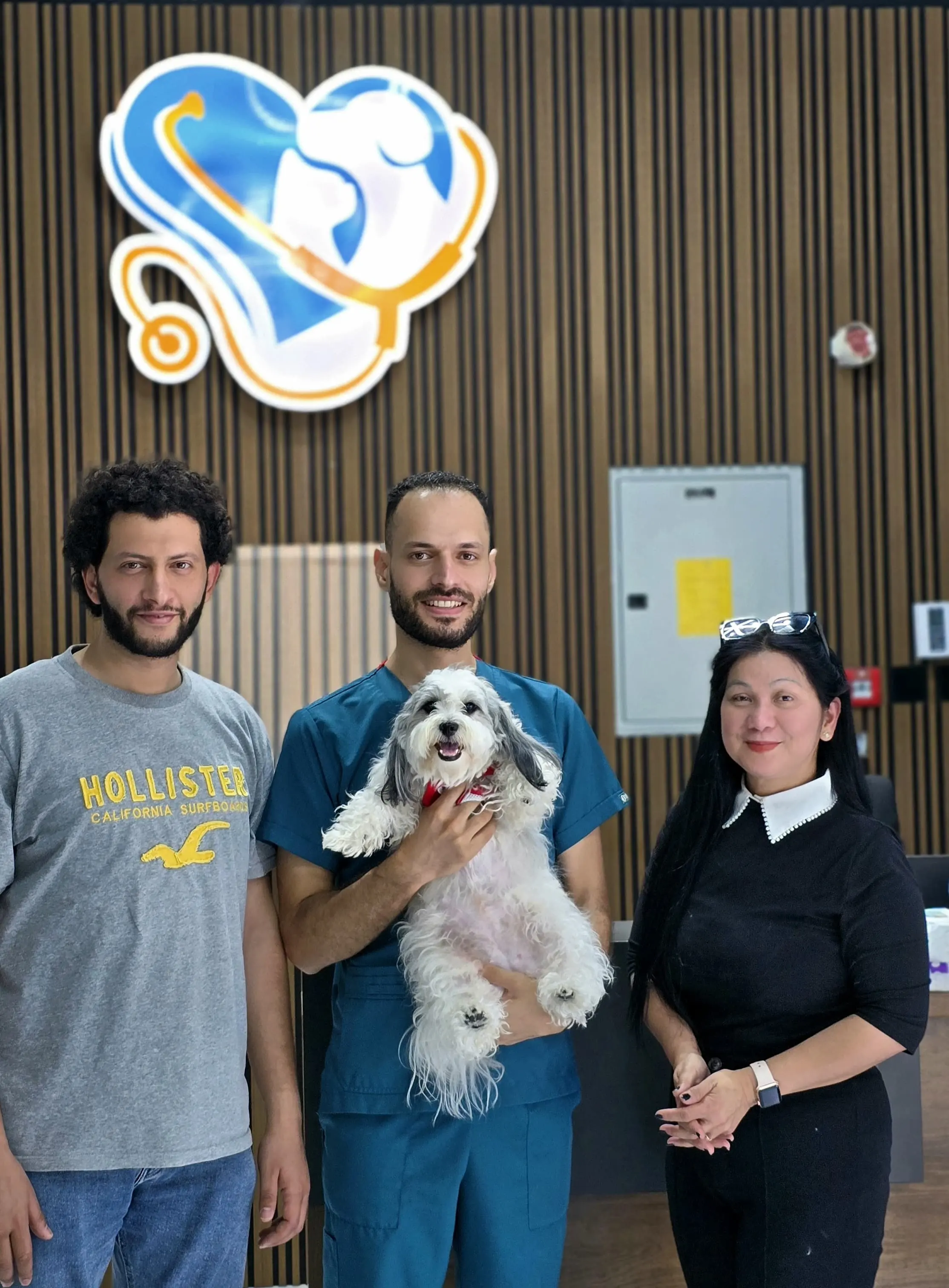 The Petbook team with a client and a happy dog under the clinic logo in Al Quoz, Dubai